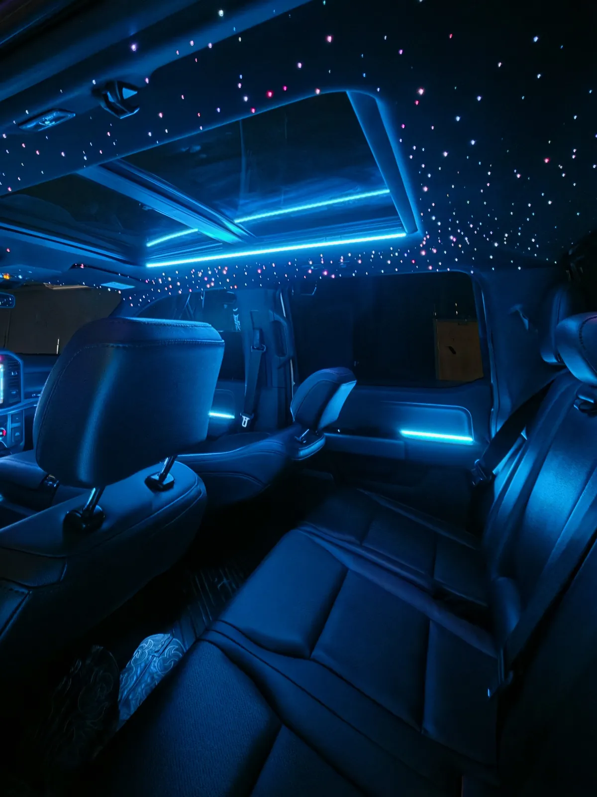 Blue ambient door and dash lighting under a starlight headliner in a Ford F-150